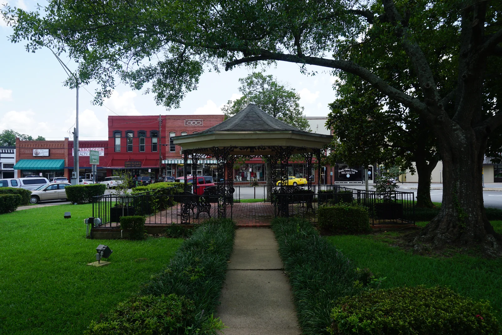 Anderson Park gazebo, shade trees, and downtown buildings in Carthage, Texas
